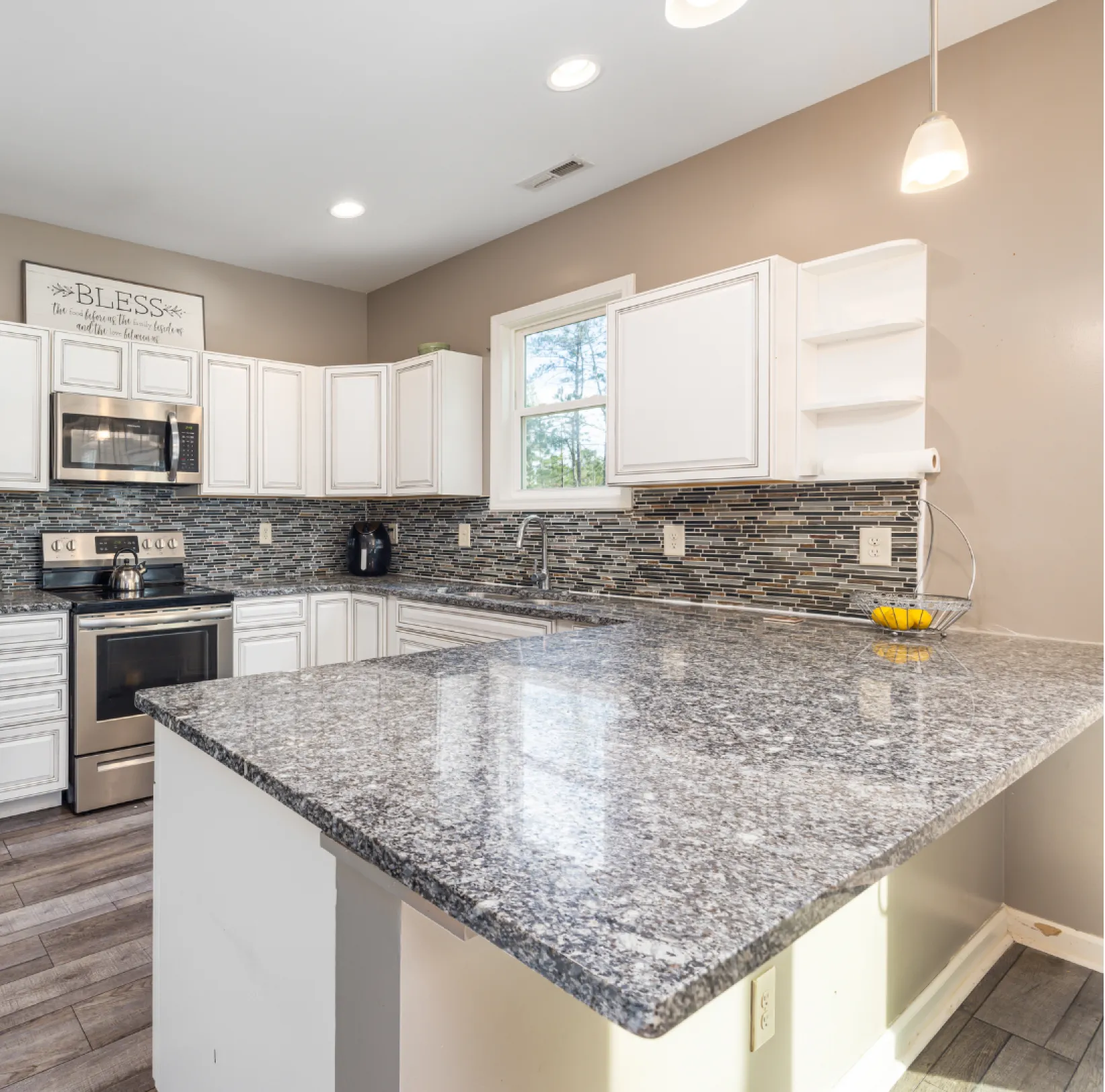 granite-1 White marble countertop with blurred modern bathroom in the background, including a window and green plant.